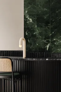 Modern bathroom with a black marble sink, two chairs, and a dining table, creating a luxurious atmosphere