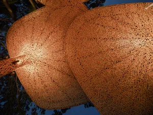 A whimsical sculpture of two metal buttocks in front of trees, creating a playful contrast between art and nature