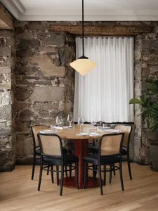 A warm and inviting dining area with a wooden table, chairs, and wine glasses, set for social gatherings or meals