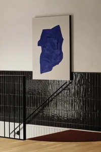 A modern staircase with black steps and a large blue painting above, creating a striking contrast in a contemporary space