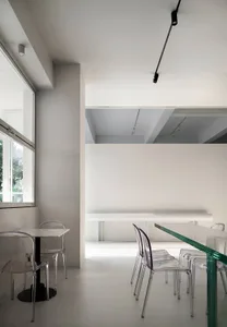 A modern restaurant interior with a large dining area featuring multiple tables and chairs, clean and well-lit atmosphere, and wooden furniture