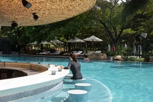 A relaxing poolside area with umbrellas providing shade, chairs and people enjoying the space