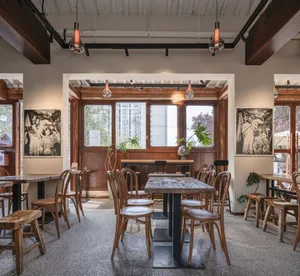 Warm and inviting restaurant interior with wooden tables and chairs, scattered dining tables, and cozy atmosphere
