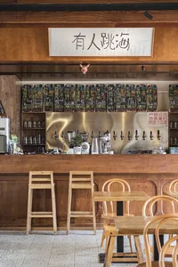 Cozy Asian restaurant with wooden floors and walls, featuring a bar area with bottles and dining tables with chairs