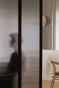 A living room with a couch and natural light coming through a glass door, two people are present in the space