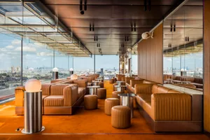 Warm and inviting restaurant interior with orange carpeting, couches, chairs, and dining tables