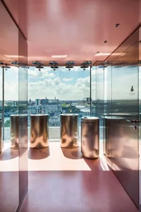 A modern bathroom with three metal sinks, a large window, and a bright and airy atmosphere