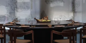 Dining area with a round table, wine glasses, and a bowl, set in a well-decorated and comfortable environment