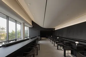 Cozy modern restaurant interior with dim lighting, multiple tables, chairs, and couches