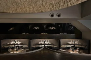 A restaurant interior with dining tables, chairs, and wine glasses, creating an inviting atmosphere for guests