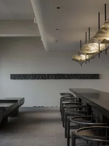 A calm and inviting restaurant interior with a large wooden table and black chairs, awaiting customers