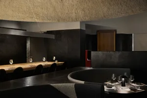 Dark and intimate restaurant interior with a circular dining table, wine glasses, and a focus on cozy ambiance