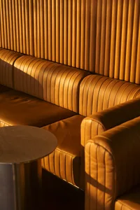 A warm living room with two couches, two benches, and brown-toned furniture, creating a comfortable seating arrangement