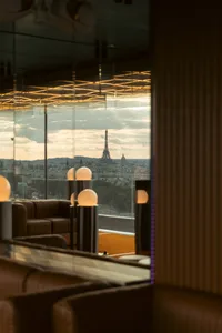Cozy Parisian cafe with a large dining area, multiple lamps, and a view of the Eiffel Tower outside