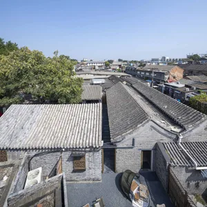 A real photo of a mixed-style courtyard with brick walls, a tiled roof, and natural light from the daytime setting