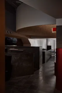 A modern bar area with a counter, dining table, and chairs, surrounded by grey walls and contemporary decor
