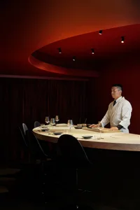 Elegant dining space with a table, chairs, and red walls, featuring wine glasses and an inviting atmosphere