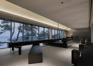 A modern living room with large windows, chairs, a dining table, and a vase, set in a bright and open atmosphere