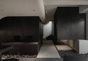 Modern living space with a black and white color scheme, featuring a couch, dining table, staircase, chairs, and a sink, with a focus on clean lines and minimalistic decoration