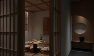 Cozy Asian-style living area with a wooden table, chairs, and a potted plant, set for relaxation and socializing
