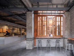 Cozy cafe interior with wooden walls and floors, three stools in front of a window, and warm lighting