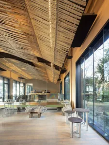 Modern restaurant interior with a bar, dining area, and ample seating options, featuring bottles and a welcoming atmosphere