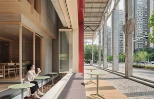 A dining area with tables and chairs arranged along a window, creating an inviting space for socializing and enjoying meals together