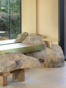 Cozy living space with a large rock wall, two large rocks, and a bench, featuring natural elements and a warm atmosphere