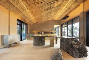 Open living area with a large stone table, wooden floors and walls, and comfortable seating arrangement