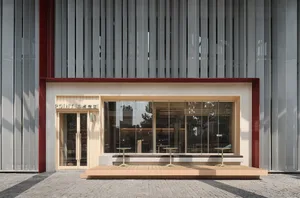 A modern building with a large window and exterior seating area featuring benches in a welcoming atmosphere