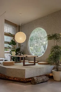 A modern living space with a round window in a white wall, surrounded by potted plants and a calm atmosphere
