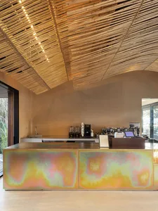A cozy coffee shop interior with a bar counter, sink, refrigerator, and various cups and bottles on display
