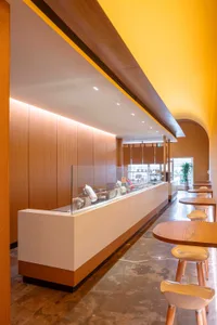 Warm and inviting cafe interior with wooden walls and floors, featuring dining tables, chairs, and decorative items