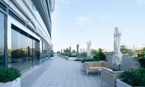 A modern outdoor patio with seating areas under umbrellas and separate chairs, featuring a comfortable and inviting atmosphere