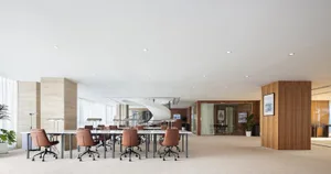 Bright and inviting open office space with a large table, numerous chairs, and potted plants