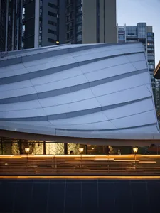 Modern building with a curved glass facade, metal frame, and multiple windows allowing natural light into the interior