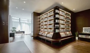 A well-lit library with numerous books on wooden shelves, arranged in an organized manner, creating a calm and studious atmosphere