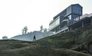 A modern building with a sleek facade featuring multiple large windows, possibly made of glass or concrete, with a well-lit atmosphere suggesting grandeur and sophistication