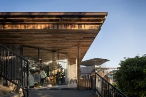 Rustic wooden building with a large roof, multiple windows, and outdoor seating area