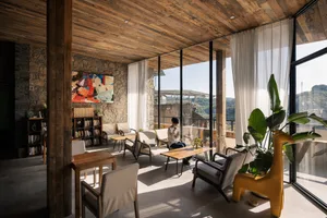 A bright and inviting living space with a large window, chairs, a dining table, and potted plants