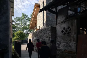 A traditional Asian building with a stone facade surrounded by trees and tourists walking around it