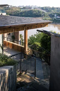 A serene outdoor patio with a wooden deck, staircase, and greenery in the background