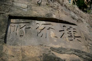 A real photo of an ancient stone wall with Chinese characters, set against a predominantly gray background, with natural light and no artificial illumination