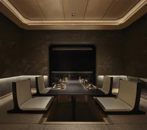 A dining area with a large wooden table and multiple chairs, set up for a meal with several bowls on the table