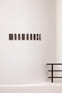 A white concrete building with a sign reading moonhouse, set against a blank background