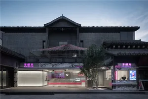 A black building with a red umbrella entrance, a balcony, and cozy interior with chairs, blending traditional and modern architectural styles
