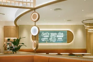 Dining area with tables, chairs, potted plants, and signs in a restaurant with a welcoming atmosphere