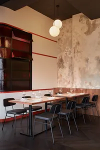 A dining area with a long wooden table surrounded by chairs, wine glasses, and an elegant atmosphere