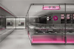 A restaurant interior with a large display case filled with donuts, pink lights, and inviting atmosphere