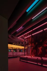 Industrial building with modern design, red neon lights, and large glass windows, featuring multiple TV screens on the walls